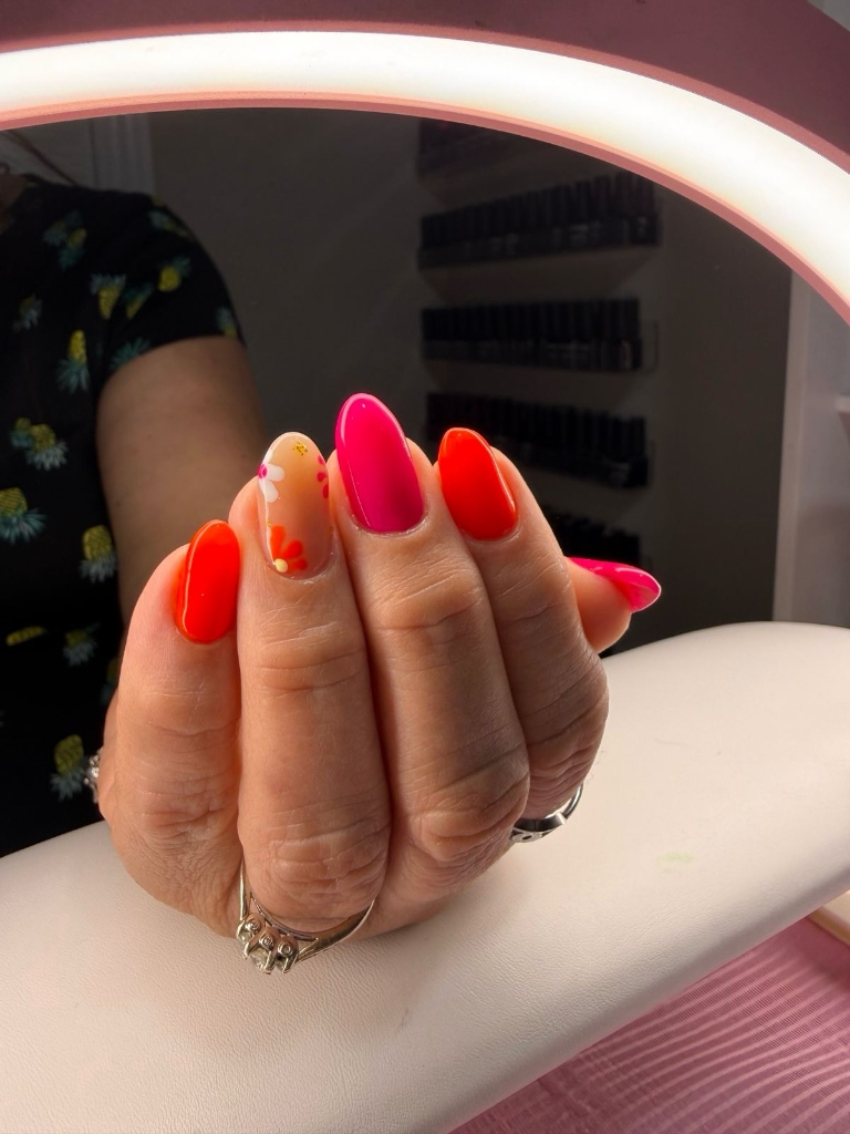 Manicura multicolor en tonos naranja, fucsia y rojo con flor pintada a mano